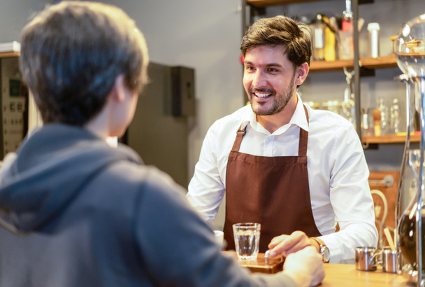 Smiling attractive bearded barista waiter standing behind counte - Foto, Imagem