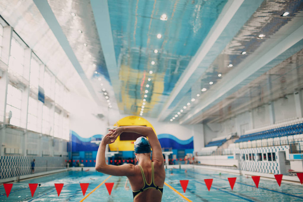 スイミングプールで泳ぐ前にウォーミングアップする若い女性の水泳選手 - 写真・画像