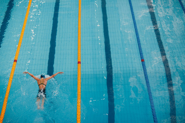 Young woman swimmer swims in swimming pool - Photo, Image
