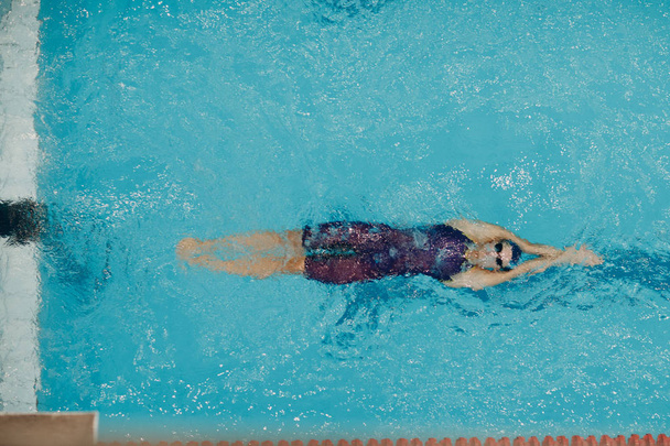 Νεαρή κολυμβήτρια κολυμπά στην πισίνα - Φωτογραφία, εικόνα