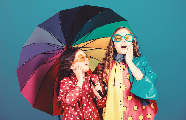 Bright umbrella. Happy childhood. It is easier to be happy together. Be rainbow in someones cloud. Rainy weather with proper garments. Walk under umbrella. Kids girls happy friends under umbrella - Zdjęcie, obraz