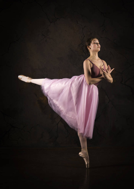 A slender girl in a pink skirt and beige top dancing ballet. - Fotó, kép