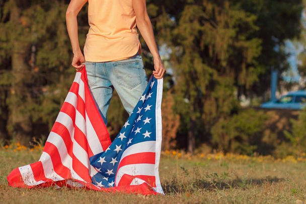 Женщина с флагом Соединенных Штатов Америки в руках, на открытом воздухе
 - Фото, изображение