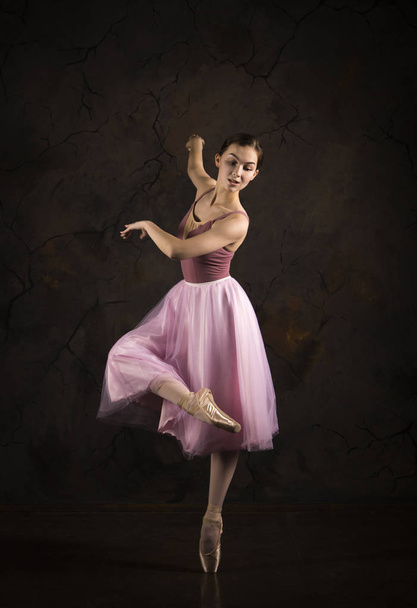 A slender girl in a pink skirt and beige top dancing ballet. - Фото, изображение