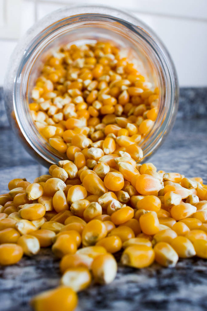 Corn used to make popcorn coming out of a glass pot but uncooked - Photo, Image