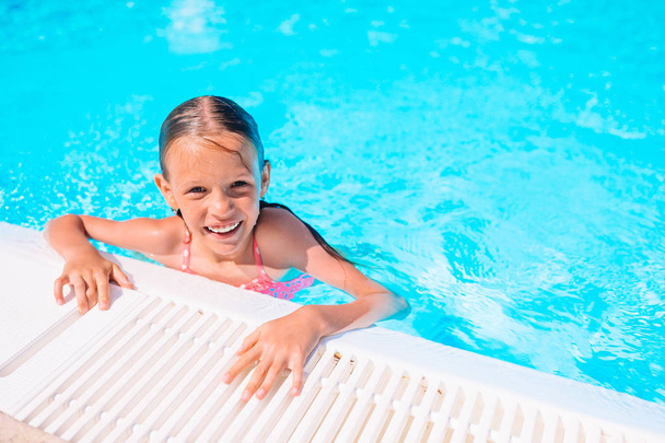 Αξιολάτρευτο κοριτσάκι που κολυμπάει στην εξωτερική πισίνα - Φωτογραφία, εικόνα