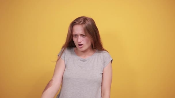 брюнетка дівчина в сірій футболці над ізольованим помаранчевим тлом показує емоції
 - Кадри, відео