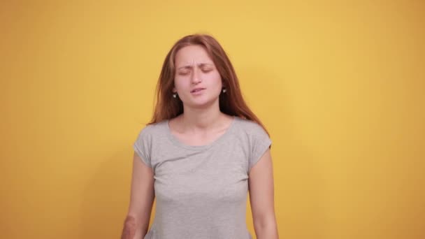 брюнетка дівчина в сірій футболці над ізольованим помаранчевим тлом показує емоції
 - Кадри, відео
