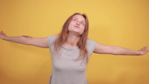 brunette girl in gray t-shirt over isolated orange background shows emotions - Filmati, video