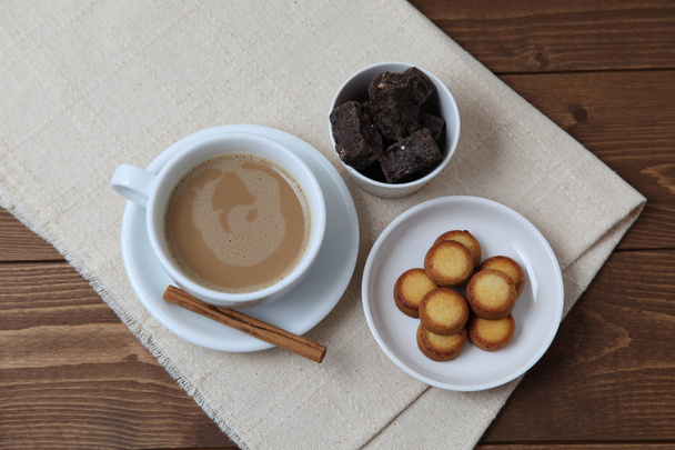 木製のテーブルの上にミルクコーヒーとクッキー - 写真・画像