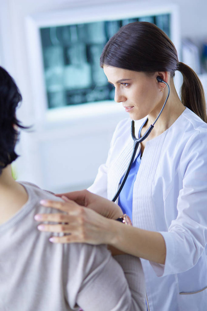 A female doctor listening a patient with a stethoscope - Foto, Bild