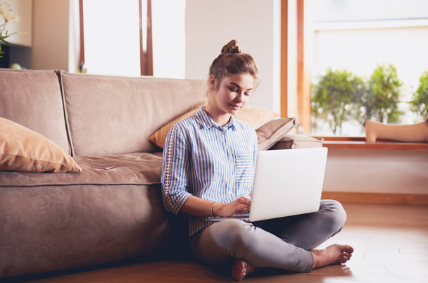 Happy woman with laptop on living room floor - Photo, Image