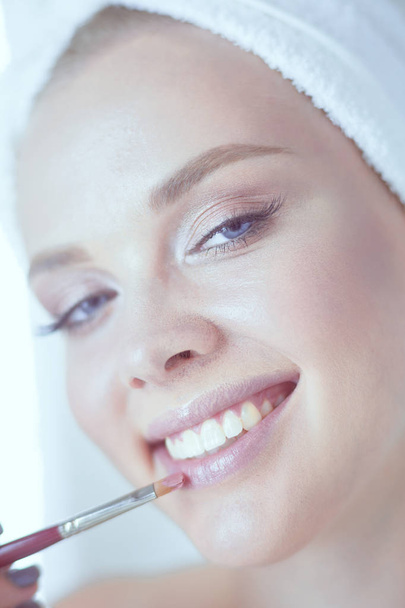 Una foto de una mujer joven aplicando polvo facial en el baño
 - Foto, Imagen