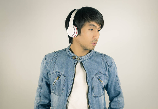 Young Asian Man in Jeans or Denim Jacket Wear Headphone Looking  - Photo, Image