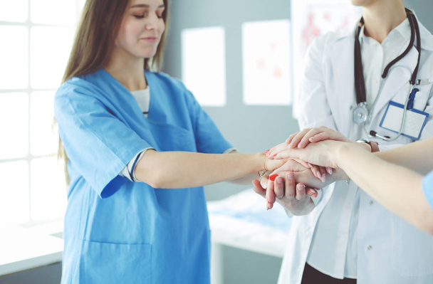 Médicos y enfermeras en un equipo médico apilándose las manos - Foto, imagen