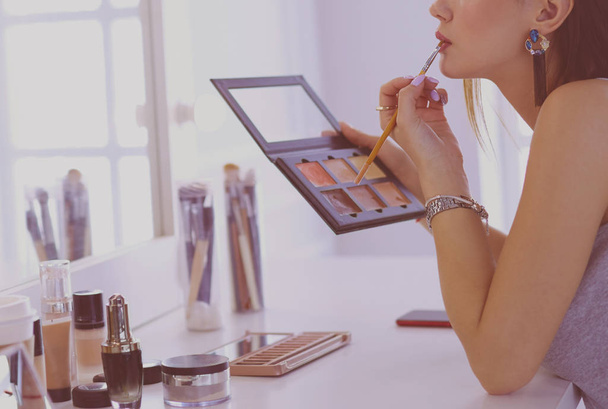 Brunette femme appliquant maquillage pour une date de soirée devant un miroir - Photo, image