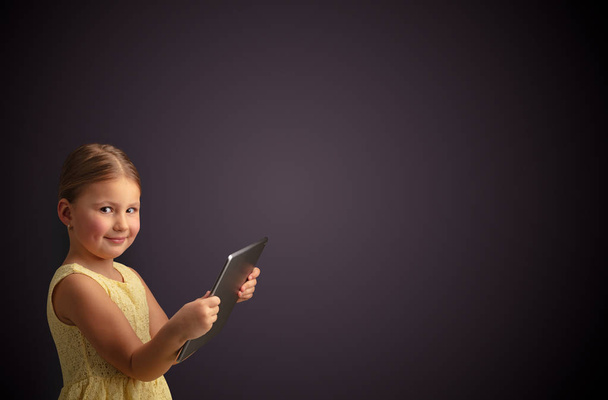 Cute little girl using tablet with dark background - 写真・画像
