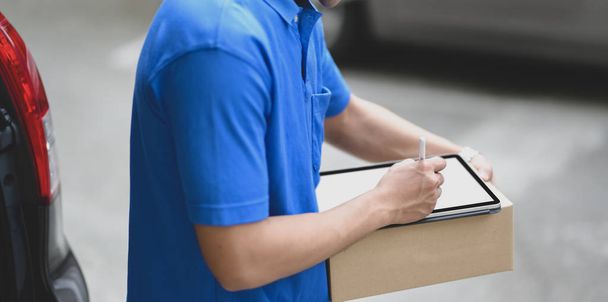 Close-up van Young delivery man die de producten aan klanten controleert - Foto, afbeelding