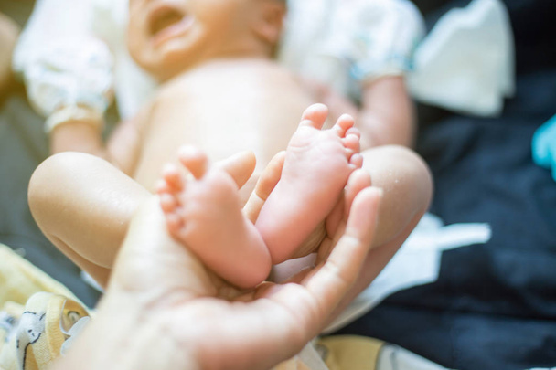 Baby voeten houden door vader hand massage selectieve focus - Foto, afbeelding