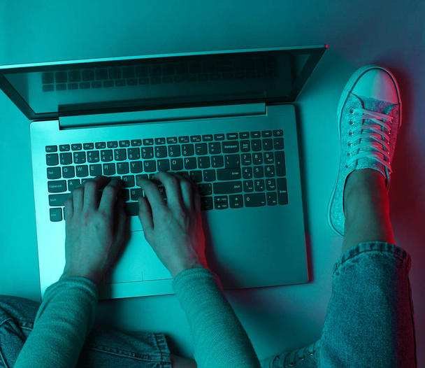 Hacker. Çevrimiçi işçi. Laptopta gece işi. Kadın eller dizüstü bilgisayarın üzerinde yazıyorlar. Koyu mavi neon ışığı - Fotoğraf, Görsel