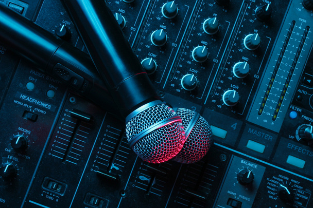 Night club, nightlife concept. Disco. Two microphone on DJ remote. Neon red blue light - Photo, Image