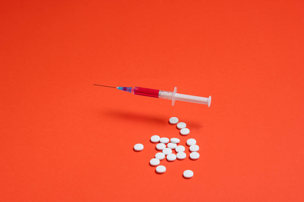 Medical minimalistic concept. Syringe, pills on orange background. - Φωτογραφία, εικόνα