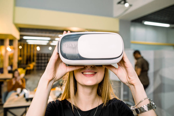 Close-up portrait of happy smiling business woman in vr goggles posing in modern office, cyber networking, future. Young team of diverse people on the background - Photo, image