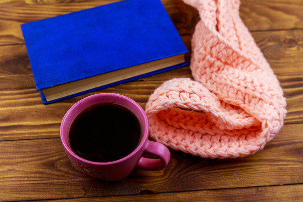Šálek kávy, pletená šála a kniha o dřevěné pozadí - Fotografie, Obrázek