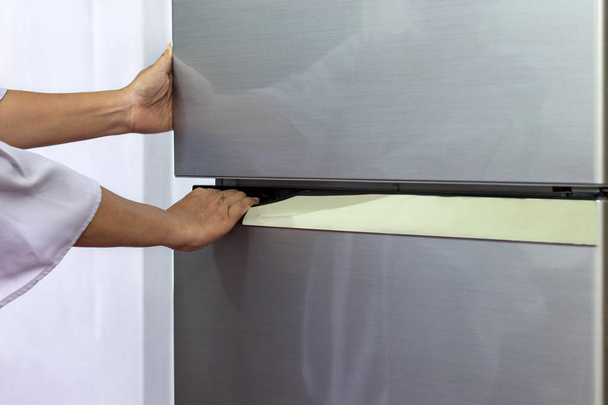 Die abstrakte weibliche Hand einer Frau öffnet einen grauen Kühlschrank - Foto, Bild