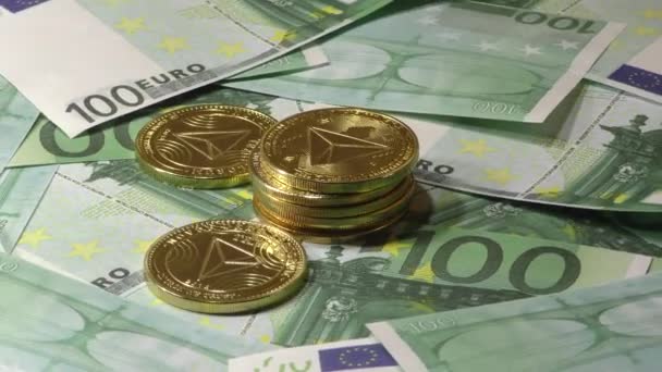 Χρυσά Tron Coin TRX κέρματα που περιστρέφονται σε χαρτονομίσματα των 100 τραπεζογραμματίων ευρώ. Παγκόσμιο εικονικό Διαδίκτυο κρυπτονομισμάτων. - Πλάνα, βίντεο