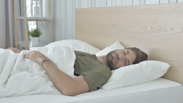 Zdenerwowany młody człowiek budzi się w szoku z łóżka - Materiał filmowy, wideo
