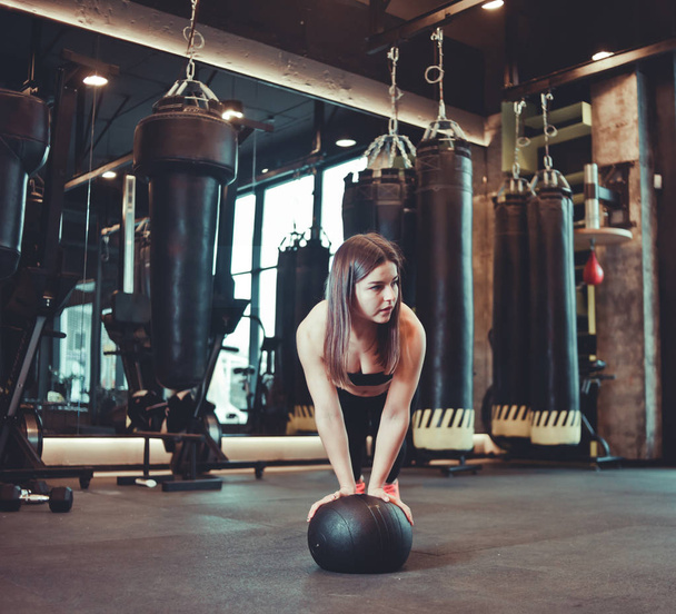 Młoda kobieta ćwicząca z piłką medyczną na siłowni. Trening funkcjonalny, dopasowanie krzyżowe - Zdjęcie, obraz