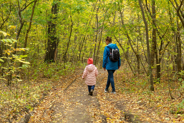 Mother and daughter are walking in the autumn forest - Photo, Image