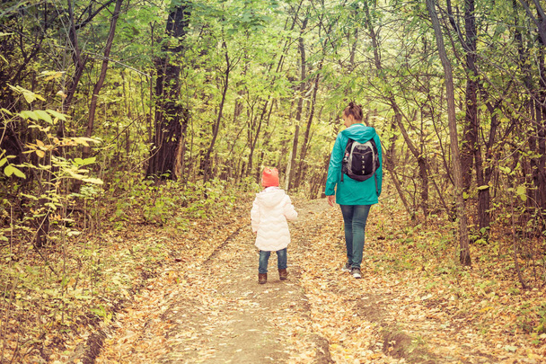 Moeder en dochter lopen in de herfst bos - Foto, afbeelding