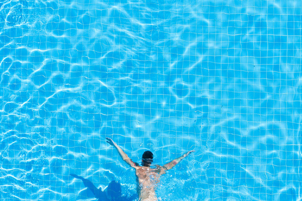 Top view of a man under water in a hotel pool. - Fotó, kép