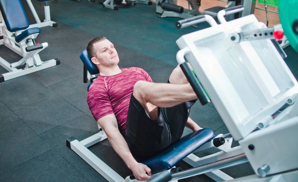 Athletic man doing exercise press leg machine in gym. Power training - 写真・画像