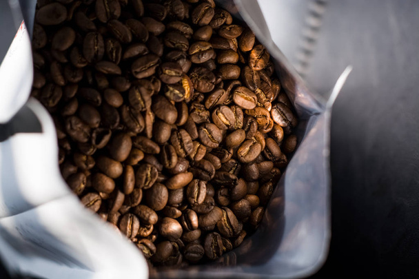 Un montón de granos de café en una bolsa sobre fondo oscuro. Arabica. Cafetería
. - Foto, Imagen