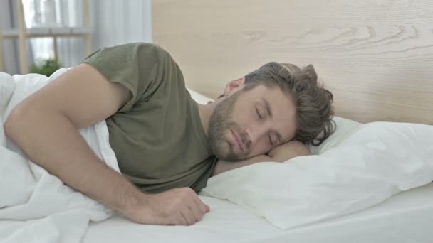 Müder junger Mann mit Nackenschmerzen beim Schlafen im Bett - Filmmaterial, Video