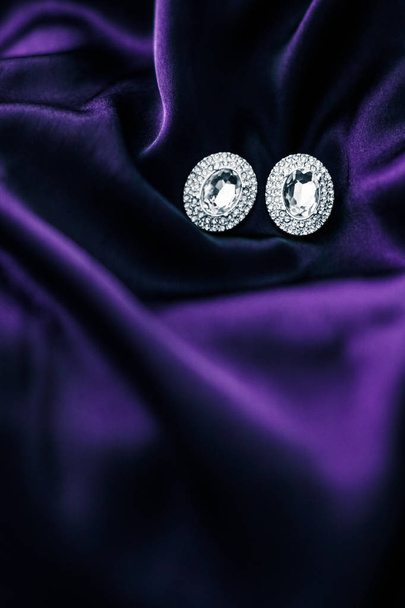 Luxus-Diamant-Ohrringe auf dunkelviolettem Seidenstoff, Urlaubs-Glam - Foto, Bild