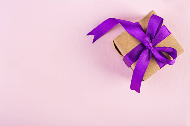 Caja de regalo con cinta púrpura aislada sobre fondo rosa. Vista superior
 - Foto, imagen