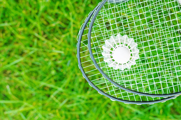 Shuttlecock and badminton rackets on a green lawn - Zdjęcie, obraz