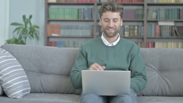 Hombre sentado en el sofá y videollamadas a través de la computadora portátil
 - Metraje, vídeo