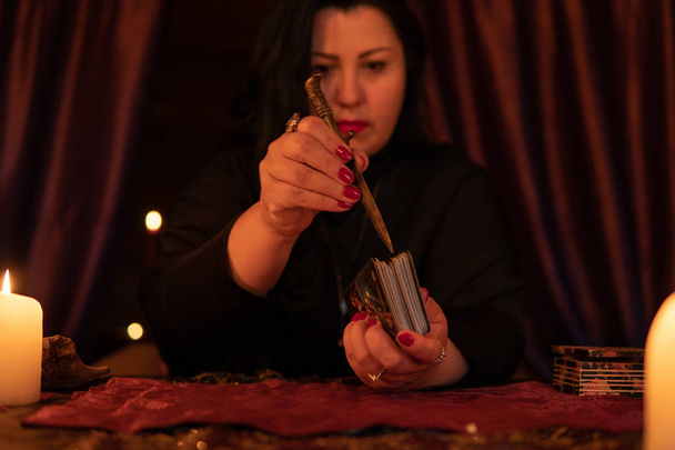 Cajero de la fortuna mujer en habitación oscura con un montón de adivinanzas velas en una baraja de cartas del tarot
 - Foto, imagen