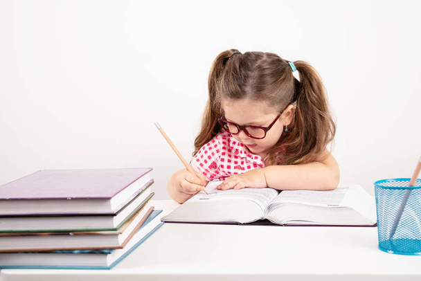 sarışın küçük sevimli kız beyaz arka plan üzerinde kitaplar üzerinde eğitim. - Fotoğraf, Görsel