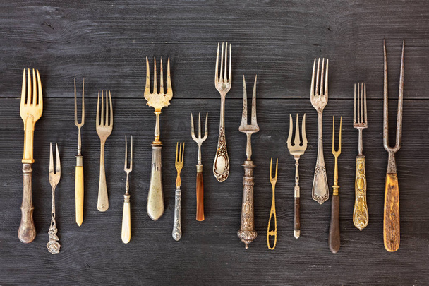 Top uitzicht op verschillende vorken, oude gebruiksvoorwerpen. Platte lay op rustieke houten achtergrond. Antieke keukengerei achtergrond - Foto, afbeelding
