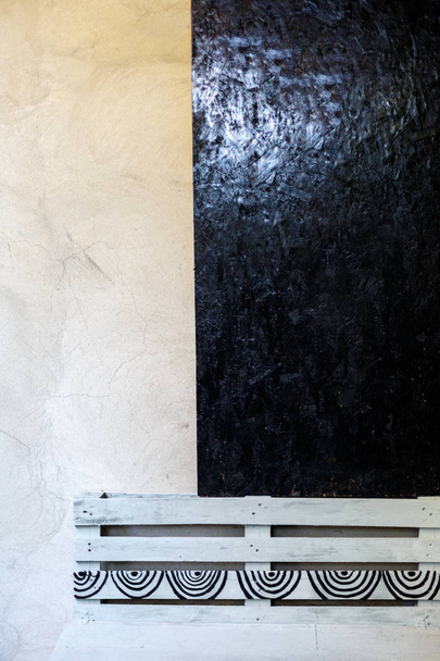 Wood texture painted by black oil paint. Beige wall and gray bench. - Photo, Image
