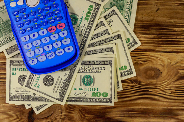 Taschenrechner und amerikanische Dollarnoten auf einem Holztisch. Ansicht von oben - Foto, Bild