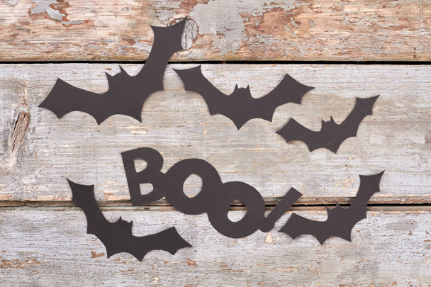 Black paper bats on wooden background. - Photo, Image