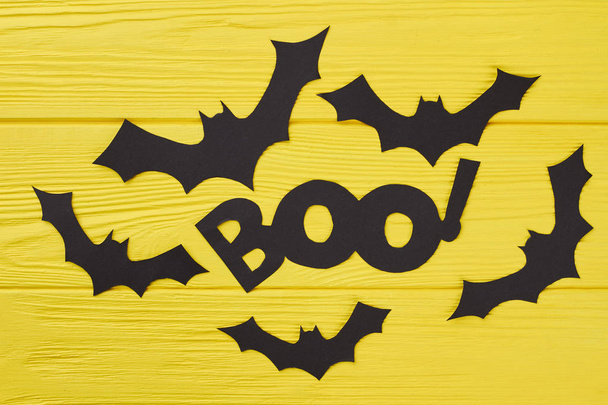Black paper bat cutouts on yellow background. - Photo, Image