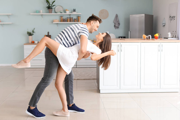 Ευτυχισμένο νεαρό ζευγάρι που χορεύει στην κουζίνα - Φωτογραφία, εικόνα